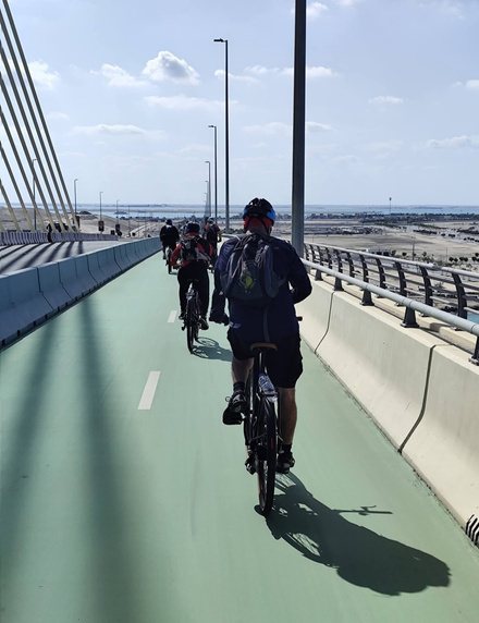 רוכבים על שביל אופניים ירוק לאורך גשר באבו דאבי